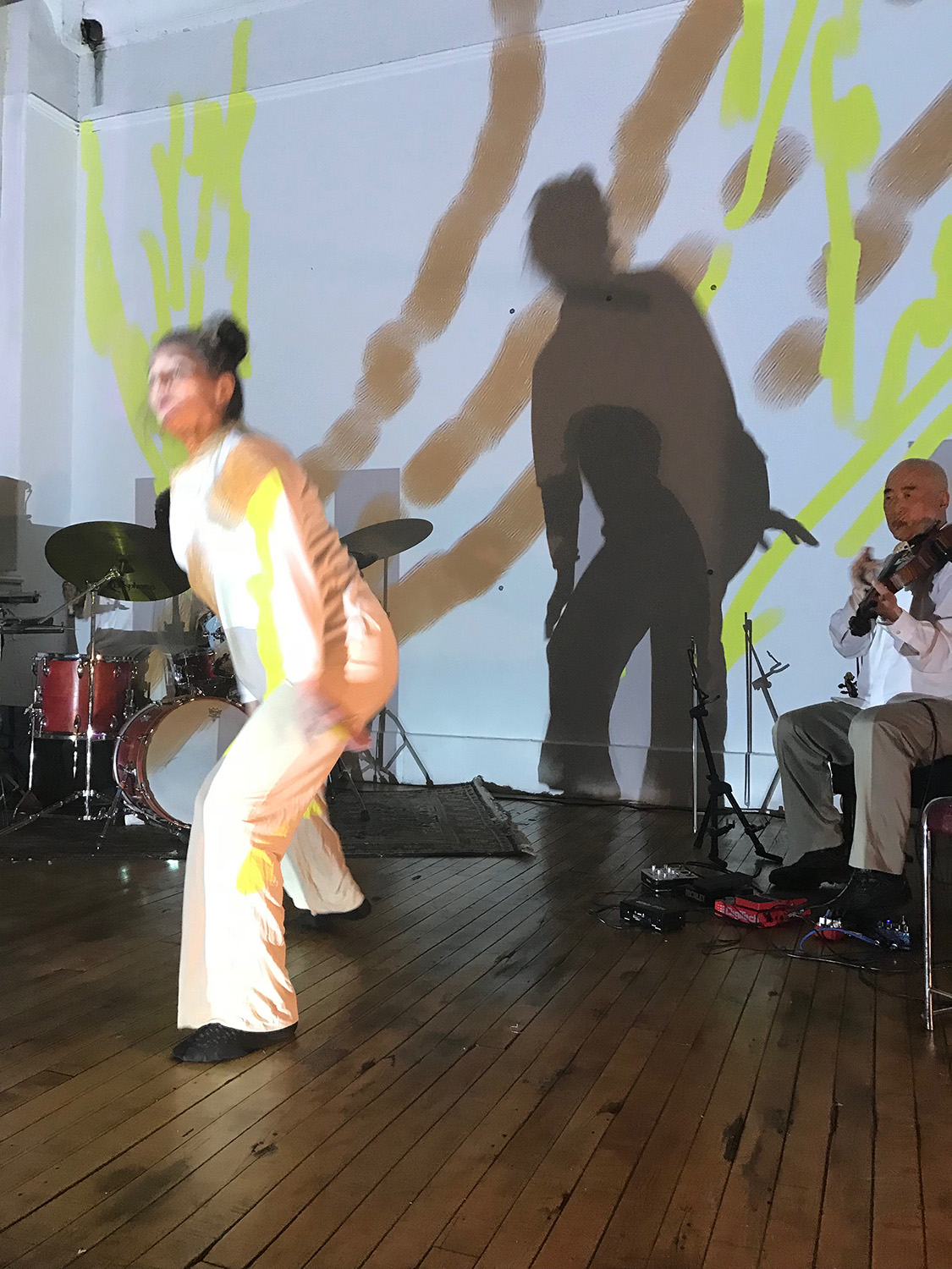 patricia nicholson dances with with jason kao hwang playing violia before a painted wall