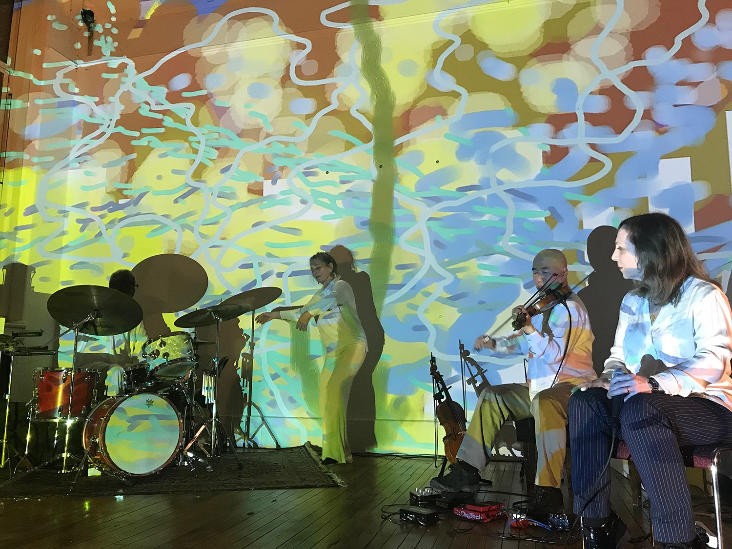 patricia nicholson dances with with jason kao hwang playing violia before a painted wall