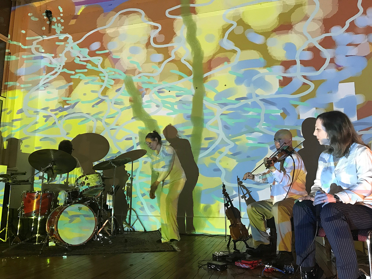 patricia nicholson dances with with jason kao hwang playing violia before a painted wall