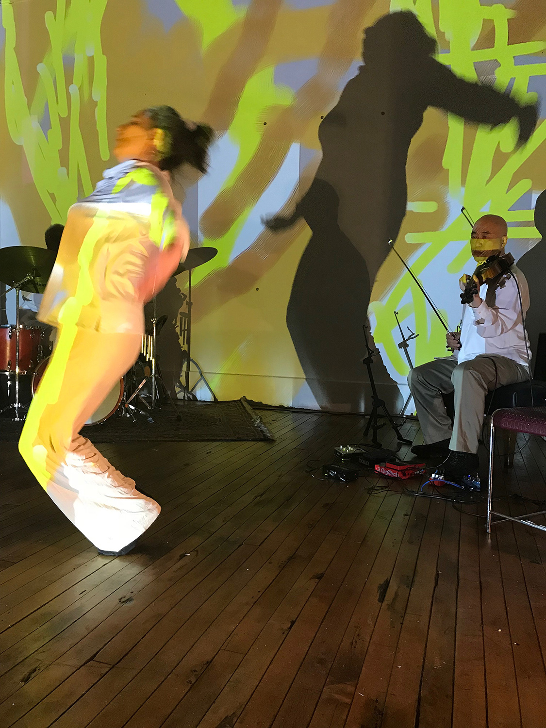 patricia nicholson dances with with jason kao hwang playing violia before a painted wall